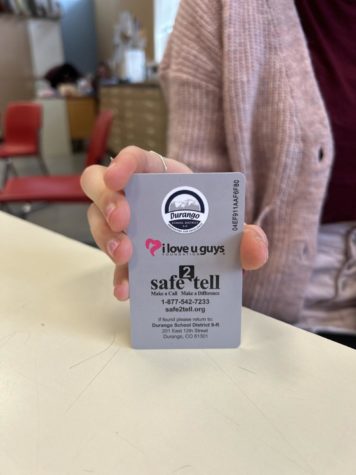 A DHS student holding their ID which has Safe2Tells number on the back, on February 14, 2023.  