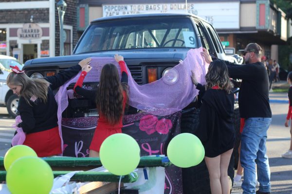 DHS Cheerleaders putting pink ribbon over the front of their homecoming float on 2nd ave and 5th street. At the homecoming parade on October 17, 2023 clubs and groups needed to complete their floats before showing them off downtown. 